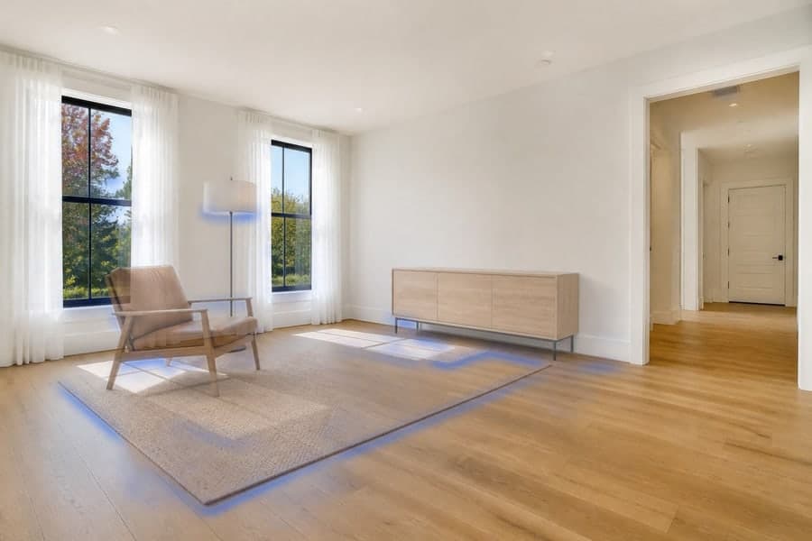 A bright, nearly empty room with the household's rug still rolled up and boxes waiting, and a translucent view of that same rug laid out across the floor